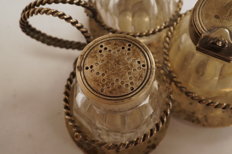 A late Victorian silver small cruet stand, with three mounted glass bottles, all Hukin & Heath, Birmingham, 1897, one associated bottle London, 1891, diameter 10.9cm, together with three assorted silver napkin rings, a s